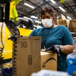 Amazon worker in fulfillment centre packing box