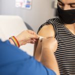 A masked person receiving the COVID-19 vaccination
