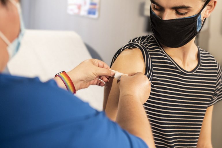 A masked person receiving the COVID 19 vaccination