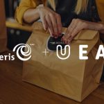 Someone folding the top part of a paper bag. The entire photo has white text on top that says Moneris plus UEAT.