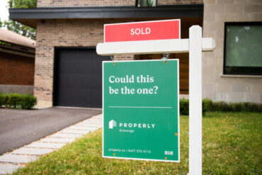 Sold sign in front of a house with properly logo