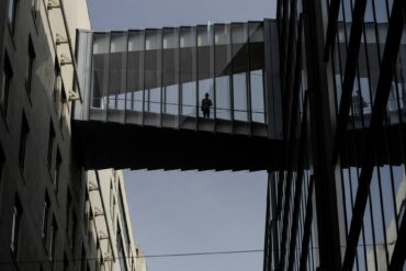 Man standing on a glass bridge looking down.