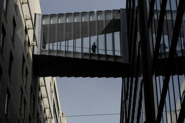 Man standing on a glass bridge looking down