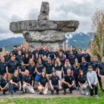 the VRIFY team in matching black t-shirts with an inukshuk in the background