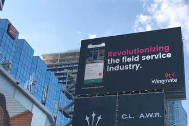 Toronto intersection with billboard for Wingmate that says "revolutionizing the field service industry"