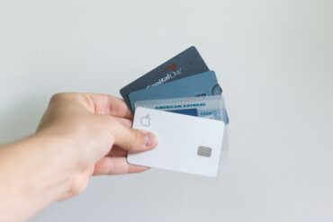 A hand holding four payment cards in a fan fashion.