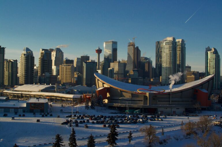 a view of calgary and the stadium from a high perch on a clear winter day with snow visible on the ground and a parking lot in the foreground