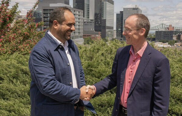 Cherif Habib, CEO of Dialogue, and Jacques Goulet, President of Sun Life, shake hands outdoors with the Montreal skyline in the background