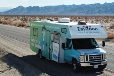 A ZayZoon-branded camper van driving across a US highway.