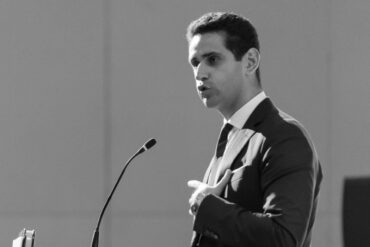 Abraham Tachjian, open banking lead, speaking in front of a microphone in a suit