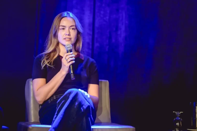 Taylor Young sits on stage speaking into a microphone.