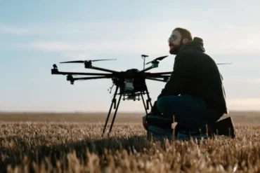 A man sits with a drone in a field